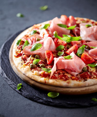 Pizza topped with black forest ham, capers and tomatoes

