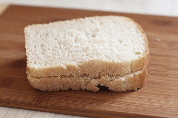 Two pieces of white bread on wooden cutting board