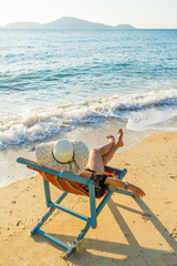 Young woman in hat sitting on beach