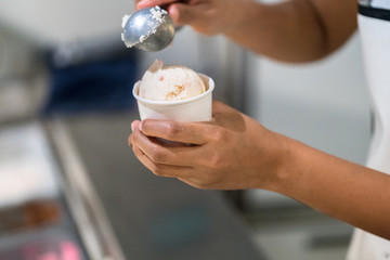 hand with ice cream scoop on cones
