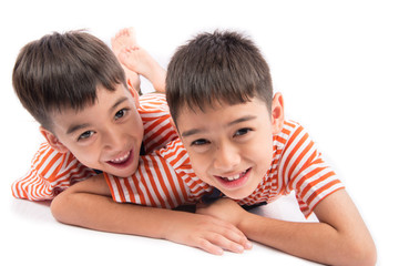 Little siblings boy brother smiling laying down together with happy face on white background