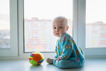 Little baby boy lonely sitting near the window