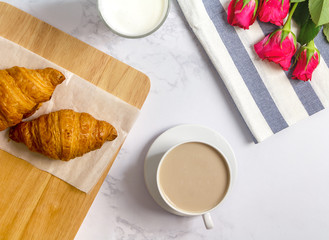 Obraz na płótnie Canvas Breakfast with croissants, pink rose flower, cutting board and b