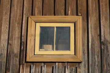 A small window on the wall of the old rustic house