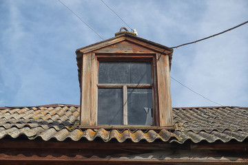 A window on the roof of the old rustic house