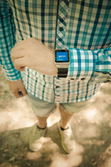 Close up shoot of young modern man checking time on smart watch display outdoors. Time, fashion and modern digital technology concepts. 