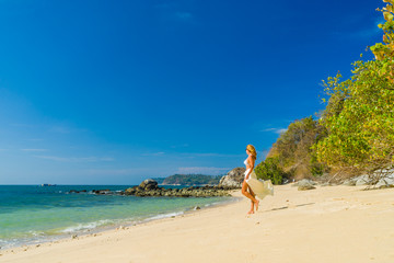 Fototapeta na wymiar Woman in white sarong stepping on the beach