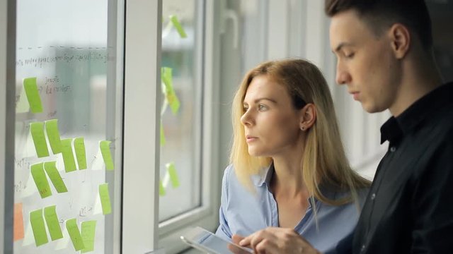 Two office workers glue colorful stickers on window