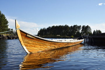 Long rowing boat laying in the water with blue sky in background, picture from Sweden.