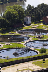 Men checking water storage tanks at sewage treatment plant