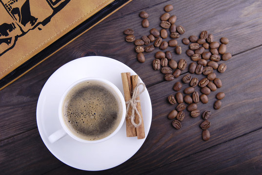 Coffee cup, beans and cinnamon on wood background