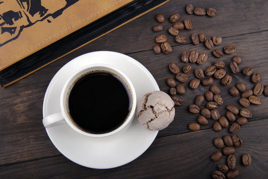 Coffee cup, beans and book on wood background