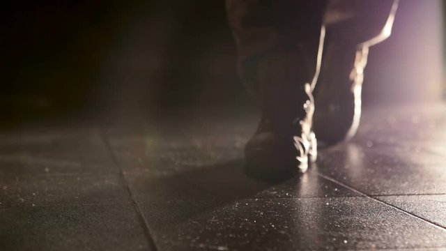 Military goes on along a dark room light. Close up shoes