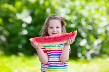 Little girl eating watermelon in the garden