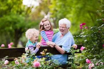 Grandmother and kids sitting in rose garden