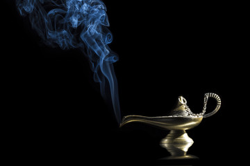 Magic lamp on black background from the story of Aladdin with Genie appearing in blue smoke concept...