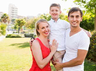 Portrait of cheerful family with boy in school age happily huggi
