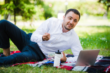 Young and attractive man relaxes in the park at lunch time