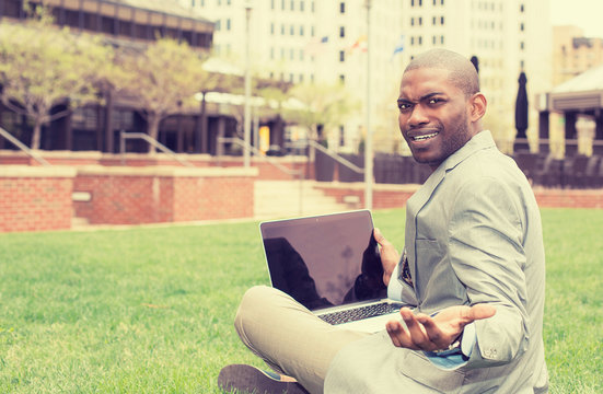Frustrated angry business man with laptop sitting outdoors corporate office