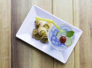 Crispy pineapple pie on rectangle white plate with blue juice. T