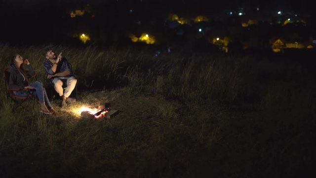 2 in 1 video! The couple sit on the background of the city. Evening night time. Wide angle. Real time capture. Crane shot with camera pitch