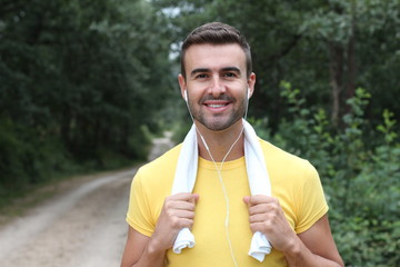Portrait of handsome young man listening to music after running. Training outdoors in the morning.