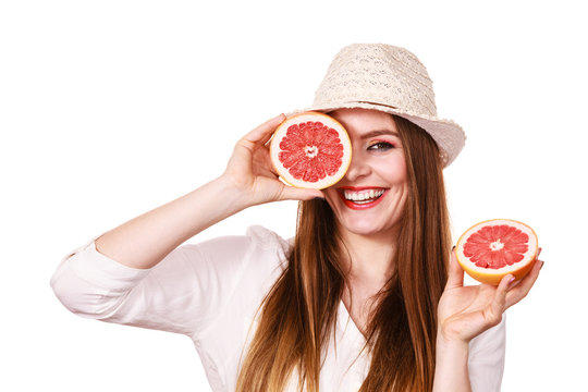 Girl covering eyes with two halfs of grapefruit citrus fruit