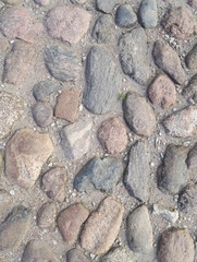 Old grey cobblestone road texture close up