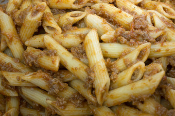 This is a photograph of Penne Pasta covered in Tomato sauce and ground beef