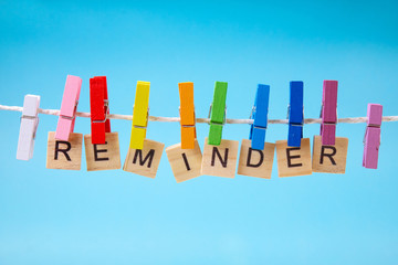 Colorful clothes pegs holding Reminder sign