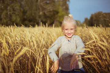 Naklejka na ściany i meble Pretty little girl walks on a yellow field