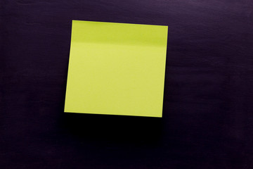 Light green sticky note with shade on blackboard