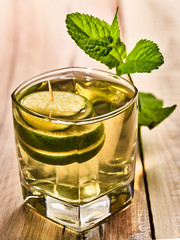 Alcohol drink. On wooden boards is glass with alcohol green transparent drink. A drink number one hundred eighty four mohito cocktail with lime. Country life. Wooden boards background.