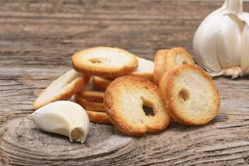Mini rolls of baked bread and garlic isolated on wooden background