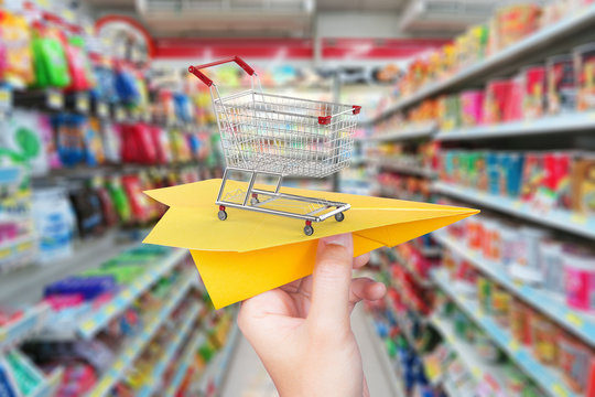 goods delivery concept with paper plane and shopping cart in supermarket