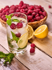 On wooden boards glass with raspberry alcohol cocktail and ice cubes. Cocktail number number two hundred thirty two cocktail raspberry mojito with raspberry bowl. Top view glass with ice cubes .