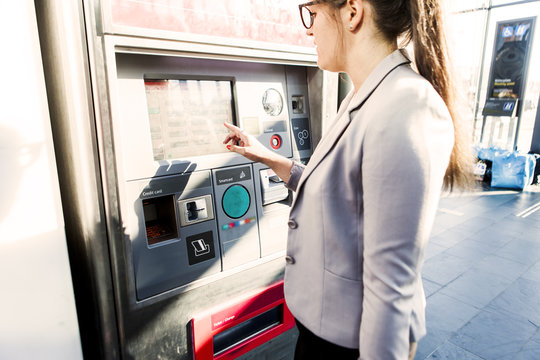 Side view of businesswoman using ticket machine at railroad station