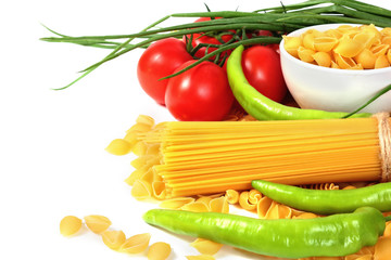 Different types of raw Italian pasta with tomatoes and other vegetables. Copy space