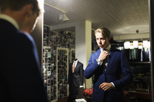 Customer adjusting tie in fitting room at clothing showroom