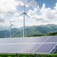 solar panels and wind turbines against mountanis landscape again