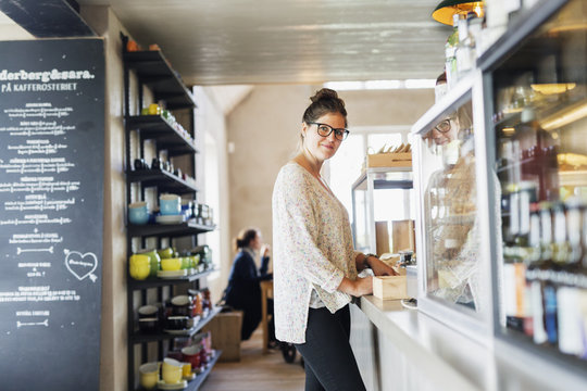 Portrait of smiling female owner standing at coffee shop
