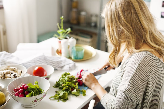 Side view of woman chopping vegetables in kitchen