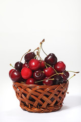 Wicker basket with ripe cherries on white background