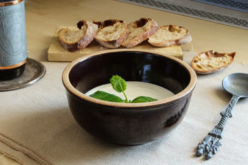 Fluffy cottage cheese with leaf of mint in bowl, French loaf, fancy spoon and glass