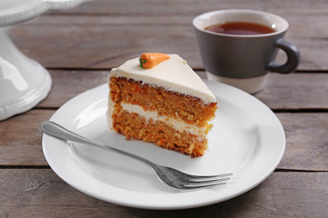Delicious carrot cake with tea on wooden table