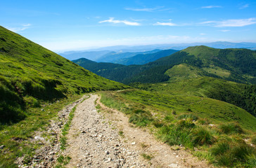 Soil road in mountains on background blue sky in summer