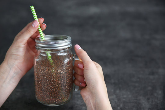 Female hands holding glass jar with chia seeds drink