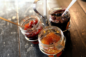 Three jars with different jam on a dark table