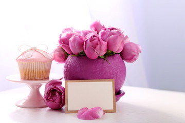 Bouquet of roses, gift card and cake on table