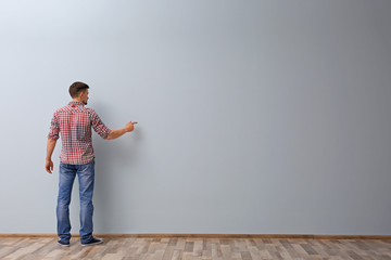 Man writing something on grey wall